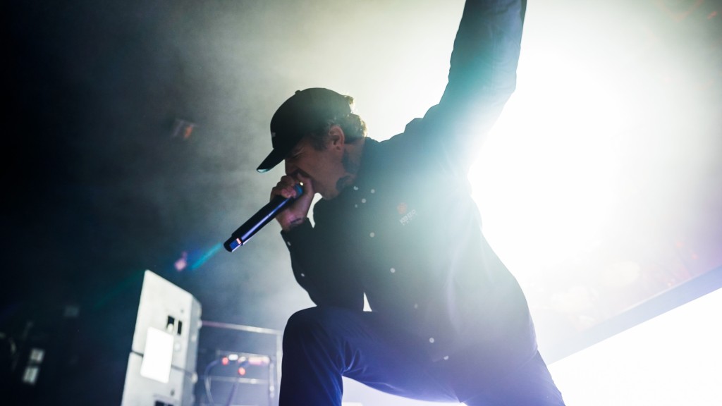 A drummer performing on stage with intense concentration, surrounded by drum equipment and stage lights.